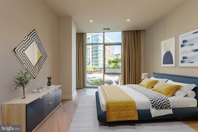 bedroom with floor to ceiling windows and light wood-type flooring