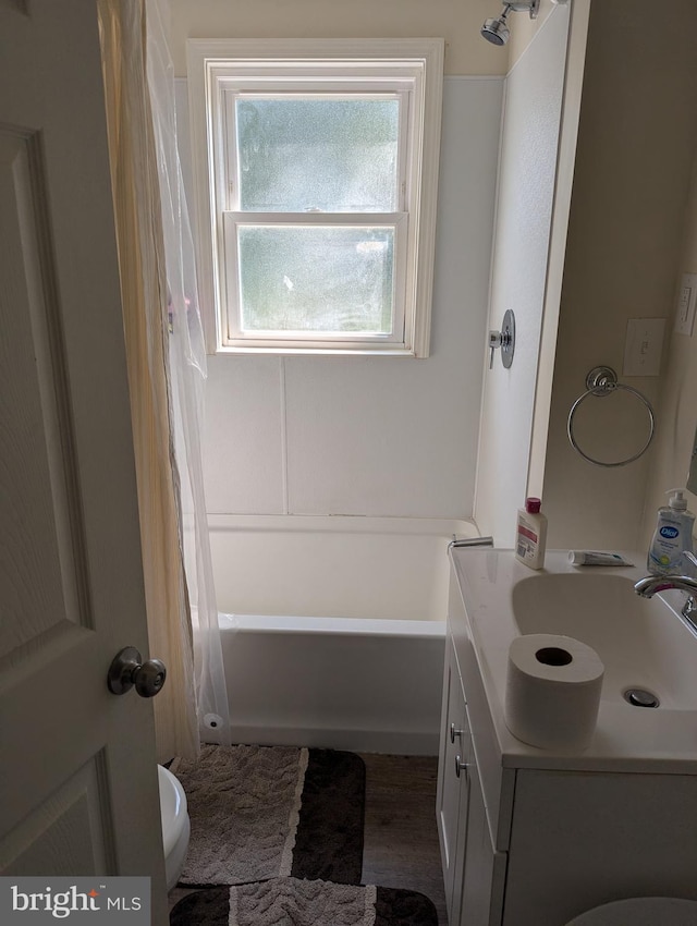 full bathroom with shower / bathtub combination with curtain, hardwood / wood-style flooring, vanity, and toilet