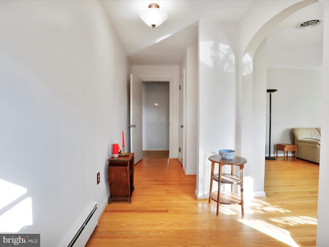 hall with light hardwood / wood-style flooring and a baseboard heating unit