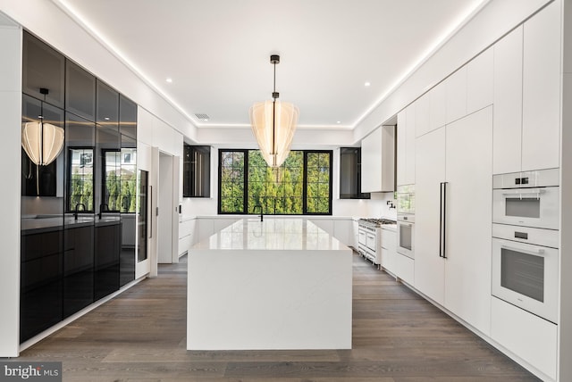 kitchen with plenty of natural light, a kitchen island, pendant lighting, and white cabinets