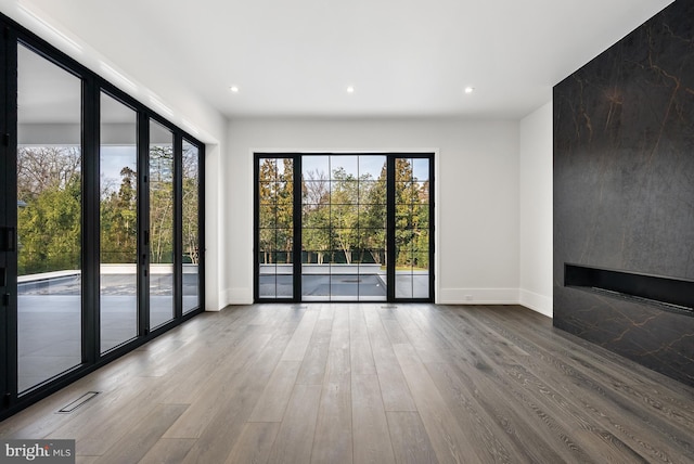 unfurnished living room featuring a healthy amount of sunlight, wood-type flooring, and a fireplace