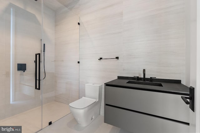 bathroom featuring toilet, vanity, tile walls, tile patterned floors, and a shower with shower door