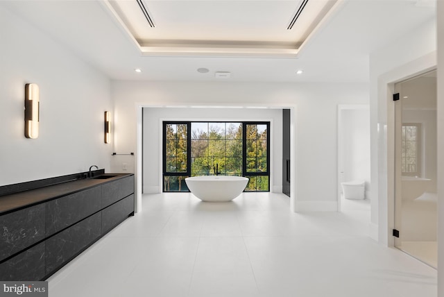 bathroom with a bathtub, vanity, a raised ceiling, and tile patterned flooring