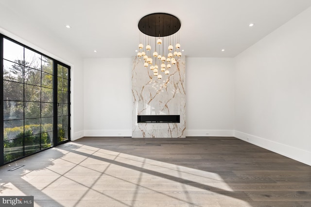 unfurnished living room featuring a premium fireplace, a chandelier, and hardwood / wood-style floors