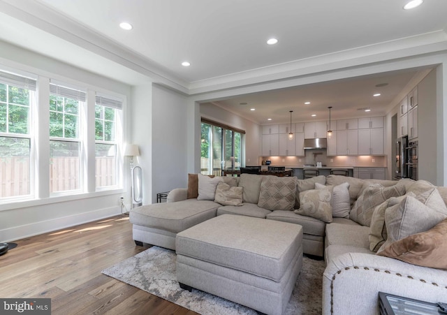 living room with a healthy amount of sunlight, light wood finished floors, baseboards, and recessed lighting