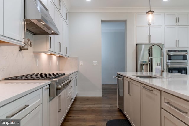 kitchen with stainless steel appliances, hanging light fixtures, white cabinets, a sink, and under cabinet range hood