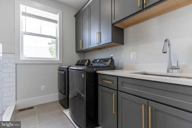 laundry area with light tile patterned floors, cabinet space, visible vents, a sink, and washer and dryer