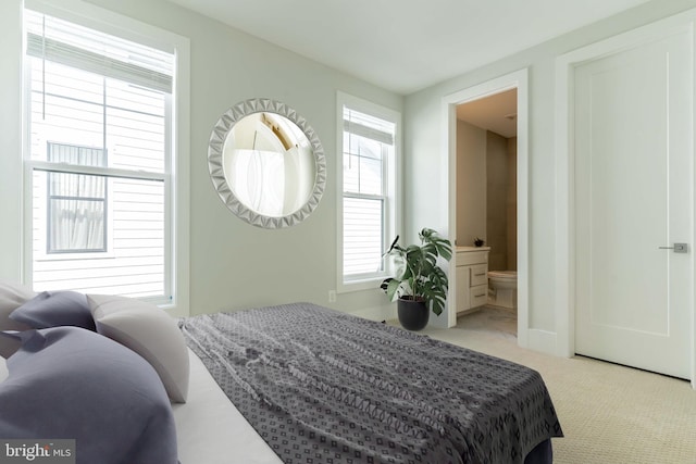 bedroom featuring connected bathroom and light colored carpet