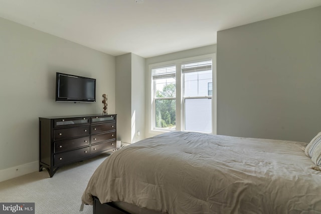 bedroom with light colored carpet and baseboards