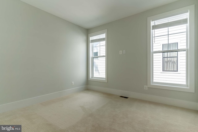 unfurnished room with visible vents, light carpet, and baseboards