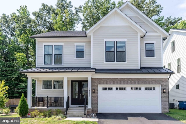 view of front facade with brick siding, covered porch, a standing seam roof, a garage, and driveway