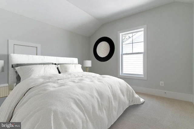 carpeted bedroom with lofted ceiling and baseboards