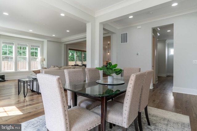 dining area with plenty of natural light, ornamental molding, and wood finished floors