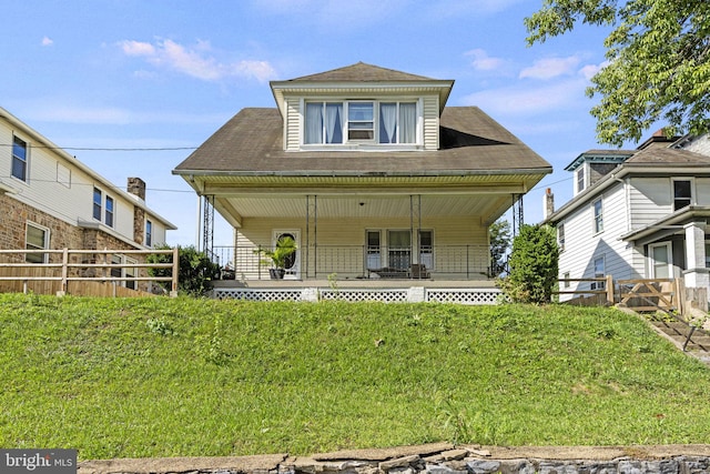 view of front of house with covered porch, fence, and a front lawn