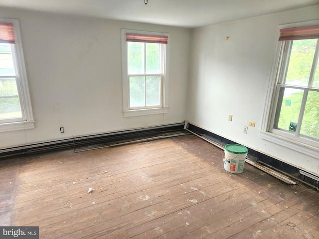 spare room featuring wood-type flooring and a baseboard heating unit