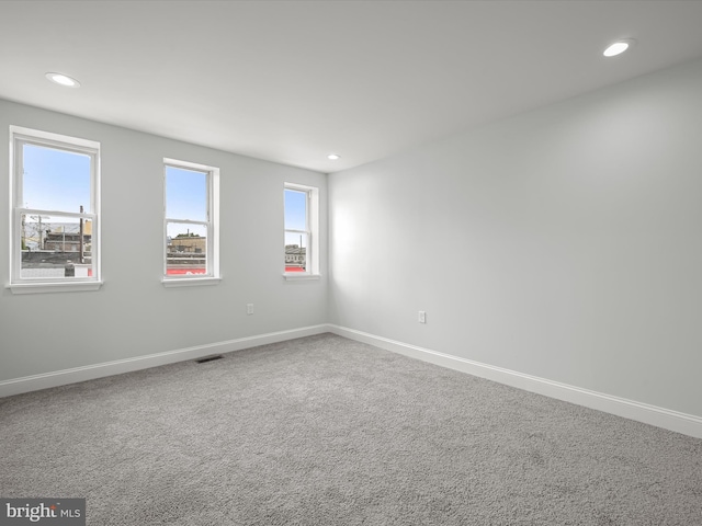 spare room featuring carpet, plenty of natural light, and baseboards