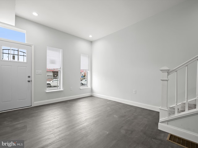 entrance foyer featuring dark wood-style floors, baseboards, stairs, and visible vents