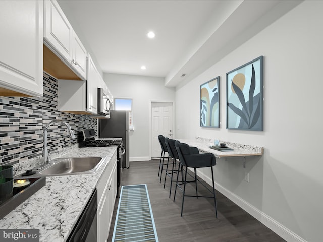 kitchen featuring baseboards, a sink, stainless steel appliances, white cabinetry, and backsplash