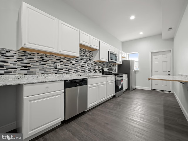 kitchen with visible vents, decorative backsplash, appliances with stainless steel finishes, white cabinetry, and a sink