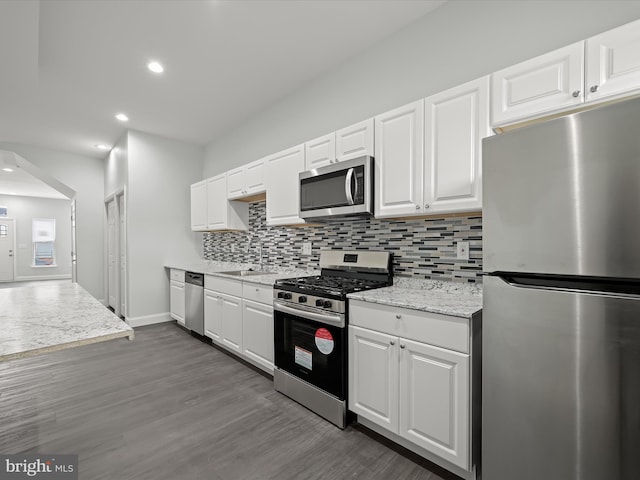 kitchen featuring dark wood-style flooring, backsplash, appliances with stainless steel finishes, white cabinets, and a sink