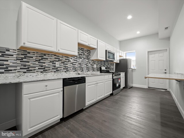 kitchen featuring white cabinets, appliances with stainless steel finishes, light stone countertops, sink, and dark wood-type flooring