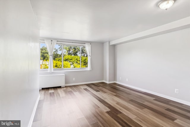 spare room with radiator heating unit and hardwood / wood-style floors