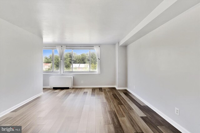 unfurnished room with wood-type flooring and radiator heating unit