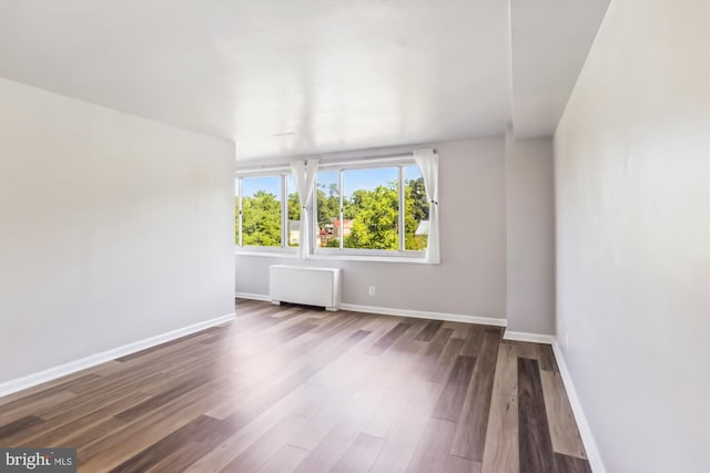 empty room featuring hardwood / wood-style flooring and radiator heating unit