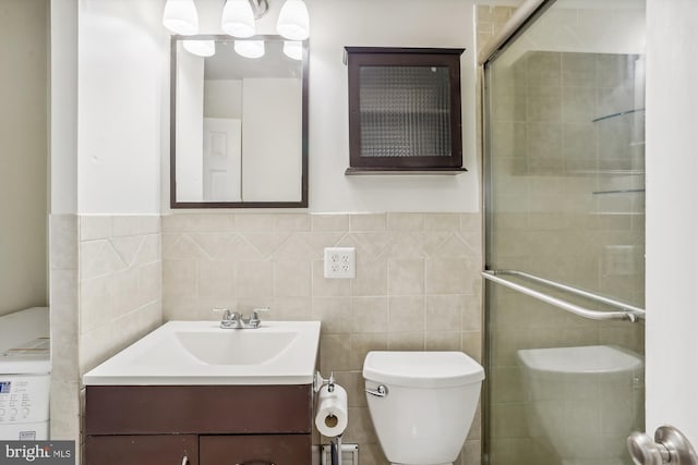 bathroom featuring walk in shower, vanity, toilet, and tile walls