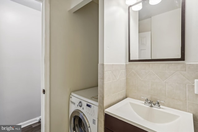 bathroom featuring vanity, washer / clothes dryer, and tile walls