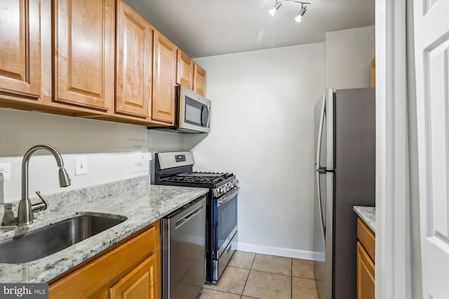 kitchen with light stone counters, stainless steel appliances, sink, and light tile patterned floors