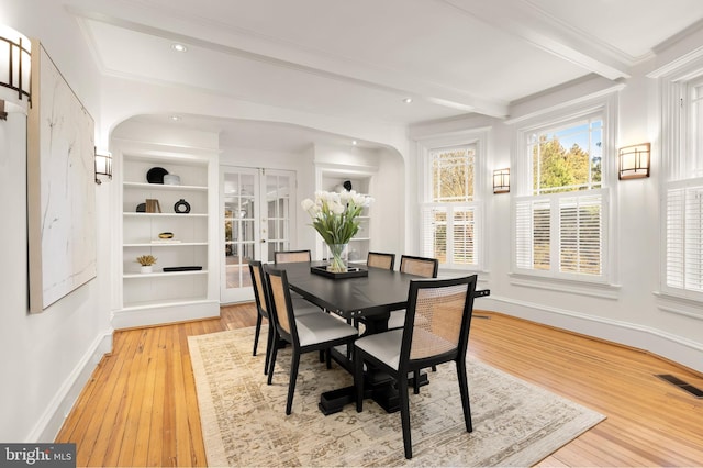 dining area with arched walkways, beam ceiling, visible vents, light wood-style flooring, and baseboards