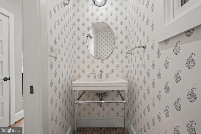 bathroom featuring a sink and wallpapered walls