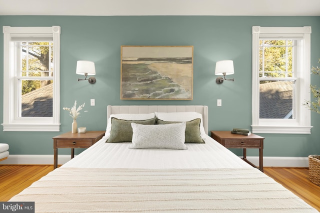 bedroom featuring multiple windows, wood finished floors, and baseboards