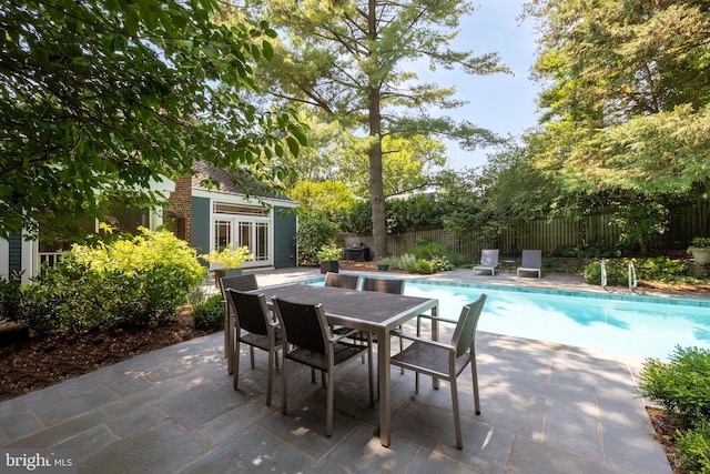 view of patio with outdoor dining area, fence private yard, a storage structure, an outdoor structure, and a fenced in pool