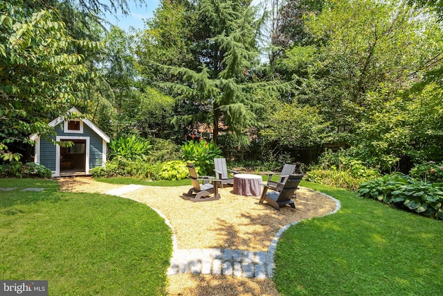 view of yard featuring a fire pit, an outdoor structure, and fence