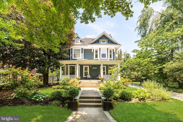 victorian house with covered porch, a front yard, and fence