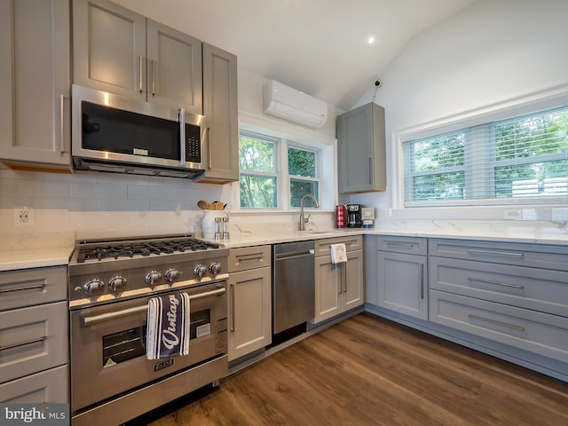 kitchen featuring dark hardwood / wood-style floors, appliances with stainless steel finishes, vaulted ceiling, tasteful backsplash, and a wall mounted air conditioner