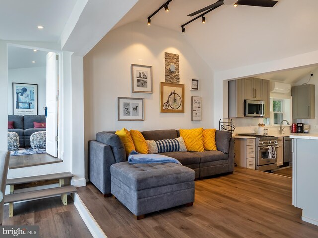 bedroom with dark hardwood / wood-style flooring, track lighting, a wall mounted AC, ceiling fan, and vaulted ceiling