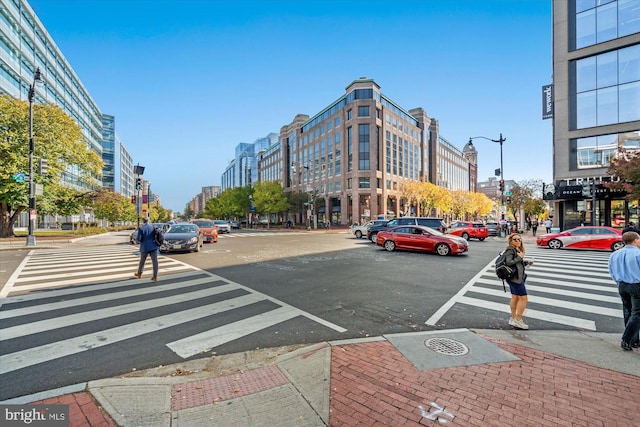 view of road featuring traffic lights, a view of city, street lighting, sidewalks, and curbs