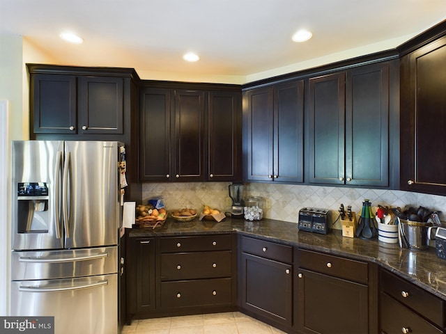 kitchen with backsplash, dark stone counters, light tile patterned flooring, stainless steel refrigerator with ice dispenser, and dark brown cabinetry