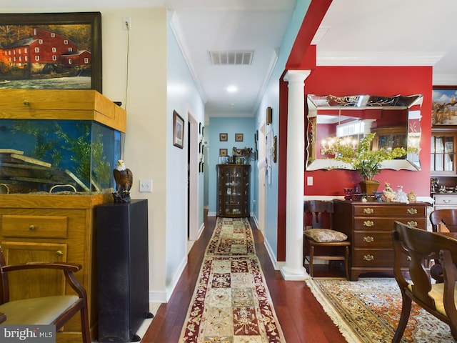 hallway with dark wood-type flooring, decorative columns, and ornamental molding