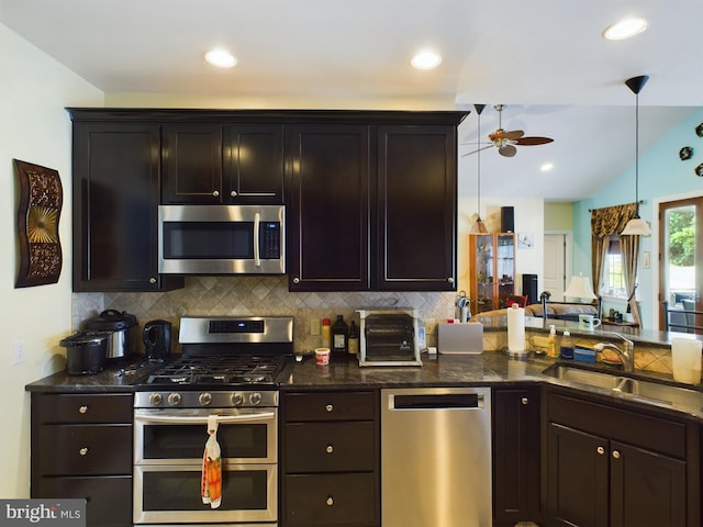 kitchen featuring lofted ceiling, backsplash, appliances with stainless steel finishes, a ceiling fan, and a sink