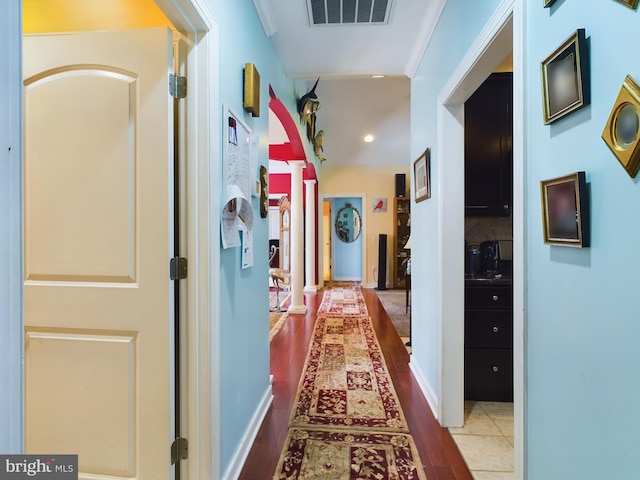 corridor featuring ornamental molding, hardwood / wood-style flooring, and decorative columns