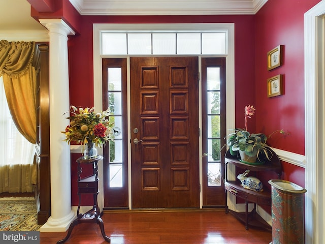 foyer with dark wood-type flooring, ornamental molding, and ornate columns