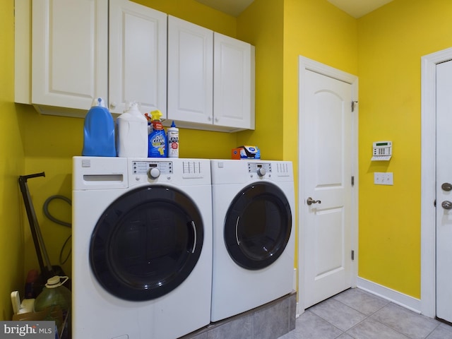 clothes washing area featuring washer and dryer, cabinets, and light tile patterned floors