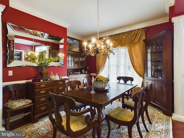 dining room with ornamental molding, a notable chandelier, light wood-type flooring, and decorative columns