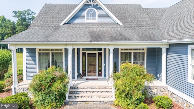 doorway to property featuring a porch and a shingled roof