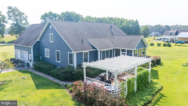 rear view of property with a garage, a lawn, and a pergola