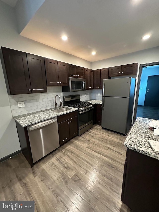 kitchen featuring sink, dark brown cabinets, stainless steel appliances, and light hardwood / wood-style floors